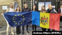 شهروندان مولداوی در رومانی پرچم‌های اروپا و مولداوی را در یک حوزه رأی‌گیری مهاجران در بخارست در دست دارند