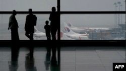 Пассажиры смотрят на самолеты компании  Malaysia Airlines на взлетной полосе аэропорта в Куала-Лумпуре. 13 марта 2014 года. 