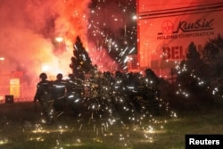 Антиправителствени протестиращи хвърлят фойерверки по полицейски служители по време на сблъсъци в Белград, 15 август.