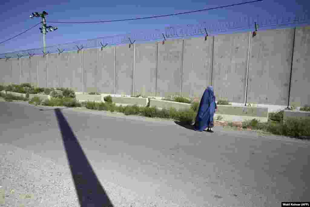 Жанчына праходзіць каля былой вайсковай базы ЗША ў Баграме 1 ліпеня.&nbsp; Некаторыя мусульмане-фундамэнталісты інтэрпрэтуюць дыскусійныя ўрыўкі з Карану як патрабаваньне да жанчын быць цалкам закрытымі, калі яны знаходзяцца ў публічным месцы.