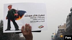 Иран өкмөтү уюштурган жүрүштүн катышуучусу  оппозиция лидери Мир Хусейн Мусавини шылдыңдаган сүрөттү булгалап көрсөтүүдө. Тегеран. 30-декабрь, 2009-жыл.