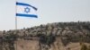 پرچمِ در اهتزاز اسرائیل، که بخشی از شهرک اسرائیلی معله آدومیم در کرانهٔ باختری در پس‌زمینه آن قابل مشاهده است