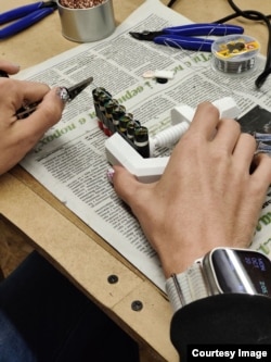 Жінка у львівській майстерні склеює батарейки для вейпів, надіслані з Лідса, у стопку, яка потім буде розміщена у павербанку