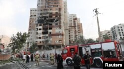 Израильдің шабуылынан бүлінген ғимараттың қасында тұрған адамдар. Тегеран, 13 маусым, 2025 жыл.