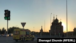 Карета скорой помощи проезжает возле церкви в городе Актобе.