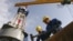Workers prepare equipment on the drilling tower of the Shakhrinav-1P exploratory well at the Sarikamysh gas field in Tajikistan.