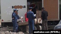 Türkmenistanda polisiýa işgärleri ýük ulagyna ýüklenýän harytlary barlagdan geçirýärler. (Illýustrasiýa suraty)
