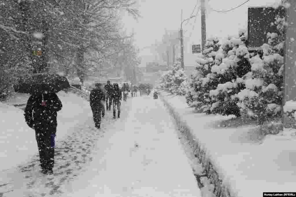 Люди с зонтами во время непрерывного снегопада.&nbsp;