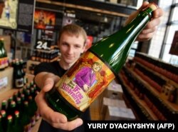 Працівник пивного ресторану з пляшкою пива з назвою «Frau Ribbentrop», на якій зображена канцлер Німеччини Ангела Меркель. Львів, 30 квітня 2015 року