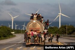 Вантажівка перевозить мігрантів на каравані, що прямує до США, проїжджаючи повз вітрову електростанцію на шляху із Сантьяго-Нільтепеку до Хучітану. Мексика
