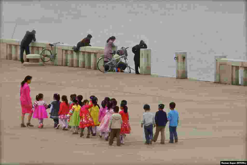 Дзіцячы сад на прагулцы ўздоўж набярэжнай. Навошта мужчына спрабуе скочыць у ваду - мы ня ведаем
