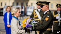 European Commission President Ursula von der Leyen (left) is given a bouquet of flowers to place at a wall in Kyiv commemorating the fallen Ukrainian soldiers in the war with Russia on September 20.