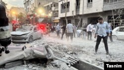 Израильдің шабуылынан бүлінген нысандар маңында жүрген адамдар. Тегеран, 13 маусым, 2025 жыл.