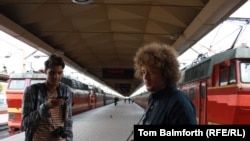 Moskwaly blogger Ilýa Warlamow (sagda) öz egindeşi bilen bile şäheriň “Leningrad” demirýol duralgasynda eli fotokameraly jemgyýetçilik ýagdaýyna syn edýär. Sentýabr, 2011.