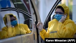 ARMENIA -- A doctor wearing a face mask and protective gear gives a call as she stands next to an ambulance at the Grigor Lusavorich Medical Centre in Yerevan, June 1, 2020