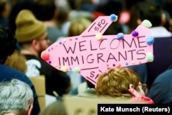 Демонстранты держат приветственные плакаты для иммигрантов во время акции протеста против депортации беженцев и граждан нескольких стран, которым Дональд Трамп во время первого срока на посту президента США запретил въезд в страну. Международный аэропорт Сан-Франциско, 2017-й год