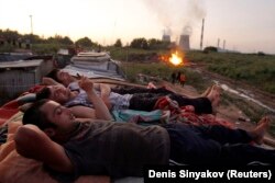 Мәскеу базарында жұмыс істейтін Тәжікстандық еңбек мигранттары жұмыстан соң демалып жатыр. (Көрнекі сурет)