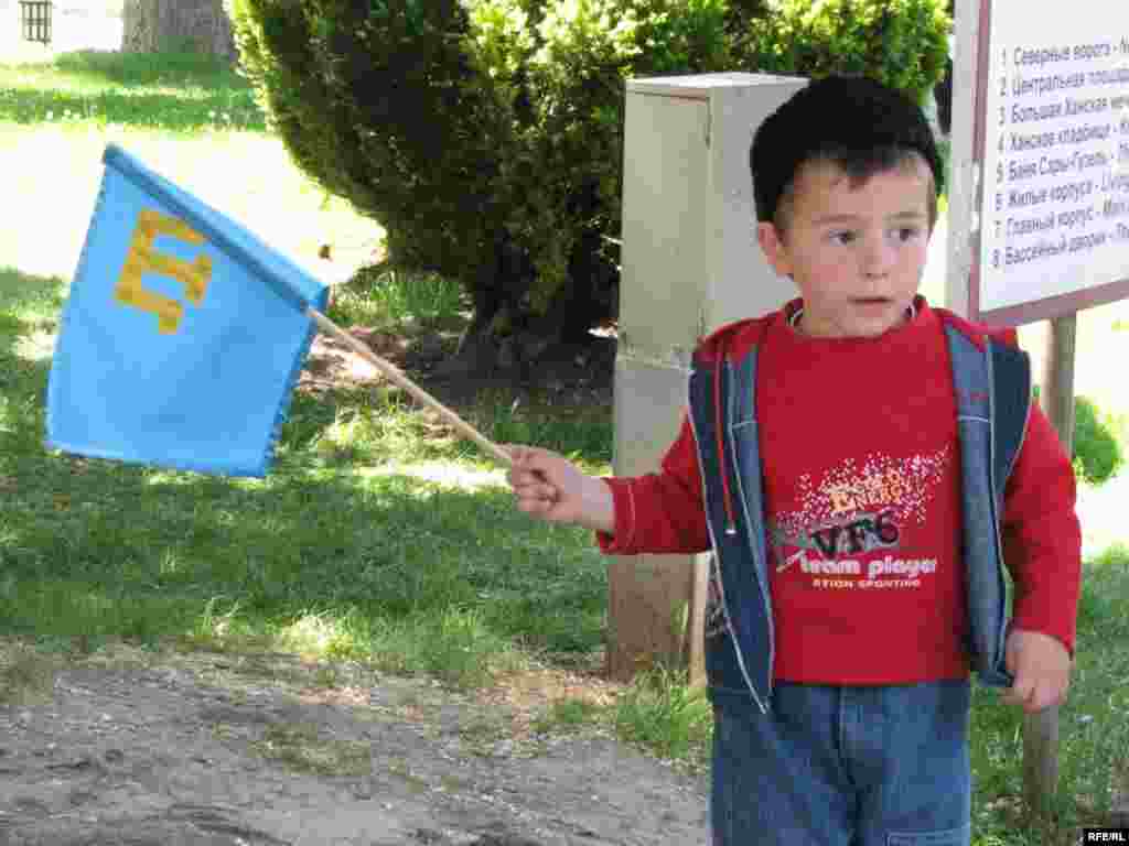 Oğlançıq Bütün dünya qırımtatar kongressi keçirilgen Bağçasaraydaki Han sarayında qırımtatar bayrağını tuta, 2009 senesi mayısnıñ 19-ı, foto müellifi Volodımır Prıtula