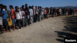 Мігранты стаяць у чарзе па бясплатныя сэндвічы, якія раздаюць валянтэры арганізацыі "Салідарнасьць Кос" на грэцкім востраве Кос, 17 жніўня 2015 году