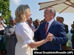 Австрия тышкы иштер министри Карин Кнайсль жана Орусия президенти Владимир Путин министрдин тоюнда бийлеп жатышат.