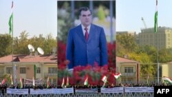 Участники демонстрации в Душанбе стоят на фоне гигантского портрета президента Таджикистана Эмомали Рахмона.