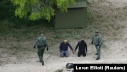 Чек ара кызматкерлери Техас Штатындагы Рио-Гранде аймагы аркылуу Мексикадан АКШга өтүп бара жаткан мыйзамсыз мигранттарды кармап алган учур. 4-апрель, 2018-жыл.