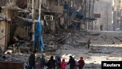 Siriýada ýumrulan jaýlaryň arasyndaky adamlar