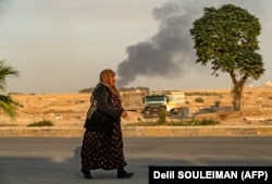 زن سوری در حال گذر در حالی‌که راس‌العین هدف حملات سنگین است