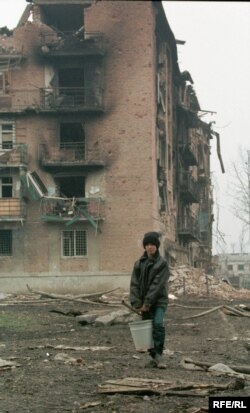 Хлопчик несе воду у підвал, де переховуються його рідні, у повністю зруйнованому російськими обстрілами і бомбардуванням Грозному. Чечня, 14 лютого 2022 року