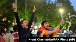 ARMENIA -- A man covered with a national flag waves an opened bottle of a sparkling wine celebrating Armenian Prime Minister's Serzh Sarkisian's resignation in Republic Square in Yerevan, April 23, 2018