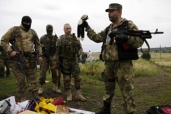 Бойовик російських гібридних сил тримає іграшку, знайдену на місці падіння уламків «Боїнга», збитого російською установкою «Бук», в результаті чого загинуло 298 людей, в тому числі 80 дітей. Донеччина, неподалік села Грабове, 19 липня 2014 року