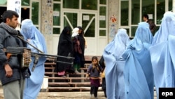 Ауған полицейі пәренжі киген әйелдерді күзетіп тұр. Әйелдер отбасындағы зорлық-зомбылық туралы семинардан шығып келеді. Герат, 2009 жылғы 24 қараша.