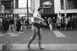 فردی به شکل و شمایل سوموکارهای ژاپنی، اواخر فروردین ماه در محله شیمن در حال سرگرم کردن مردم است