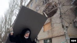 Жінка несе будівельний матеріал після обсрілів у Авдіївці, 3 лютого 2017 року