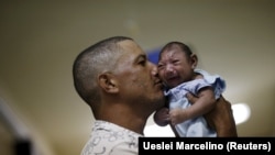 Бразилец держит на руках сына, родившегося из-за перенесенной его матерью лихорадки Зика с микроцефалией. Ресифи, 26 января 2016 года.