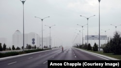 یکی از رفتگران زیر باد و باران، در یکی از بزرگراه‌های معمولاً خالی عشق‌آباد.