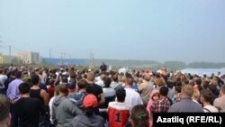 Җыелган халык митингта чыгыш ясаучыны тыңлый