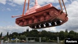Окрашенный в розовый цвет советский танк грузят на судно, чтобы доставить в Прагу. 20 июня 2011 года.