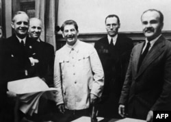 Германиянын тышкы иштер министри Йоахим фон Риббентроп (солдо), Германиянын мамлекеттик катчысынын орун басары Фридрих Гаусс, Совет мамлекетинин башчысы Иосиф Сталин (үчүнчү) жана СССРдин тышкы иштер министри Вячеслав Молотов (оңдо). 1939-жылы 23-августта тартылган сүрөт