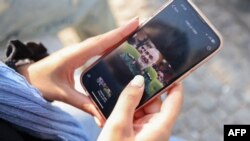 Иранская женщина в смартфоне смотрит на фотографию лидера Корпуса стражей исламской революции Ирана майора Хоссейна Салами, погибшего в результате израильского удара 13 июня 2025 гола по Тегерану