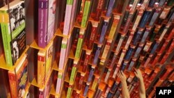 Бир басма үйүнүн өкүлү Майндагы Франкфурт шаарында ачылган 61-эл аралык китеп жармаңкесиндеги көргөзмөлөрдүн биринде текчелерге китептерди тизүүдө. Германия. 2009-жылдын 13-октябры. 