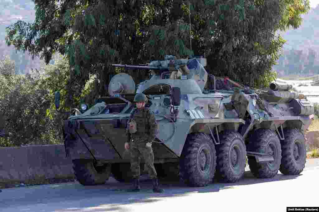 Російський солдат охороняє броньовану військову машину, у якої відмовив двигун. Біля авіабази Хмеймім. 15 грудня 2024 року. Колишній президент Сирії Башар Асад у письмовій заяві, в якій описує свою втечу з країни через наступ повстанців, стверджує, що спочатку його вивезли з Дамаска на базу Хмеймім. Звідти 8 грудня його переправили до Росії. Перед цим ця російська авіабаза &laquo;зазнала атаки безпілотників&raquo;