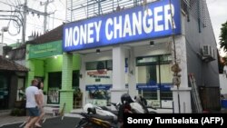 Іноземні туристи намагаються обміняти гроші в пункті обміну валют на острові Балі, Індонезія, архівне фото, 2019 рік