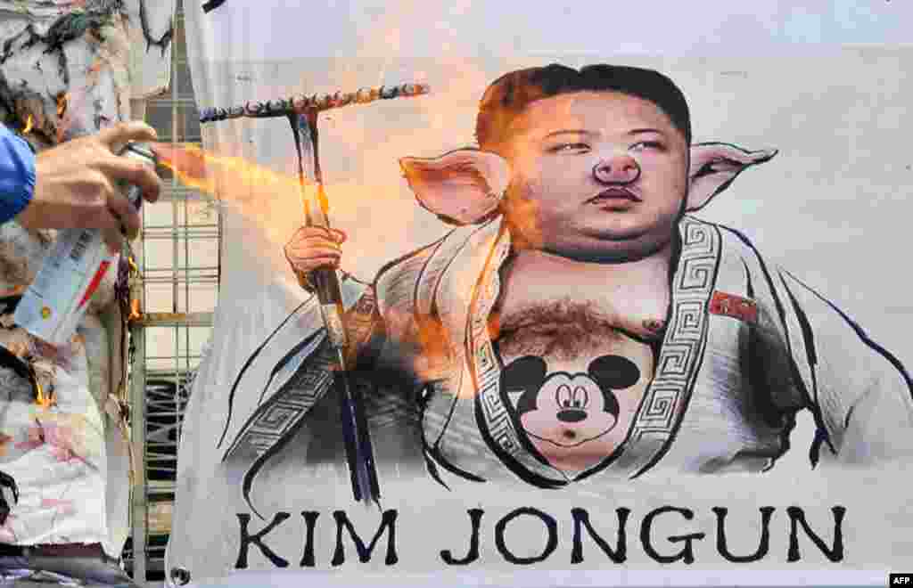 Південна Корея &ndash; активіст спалює плакат з карикатурою на північнокорейського лідера Кім Чен Ина під час мітингу в Сеулі, 18 квітня 2013 року