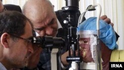 حسن هاشمی،‌ وزیر بهداشت ایران در حال معاینه چشمان سهیلا جورکش، ‌قربانی اسید پاشی اصفهان