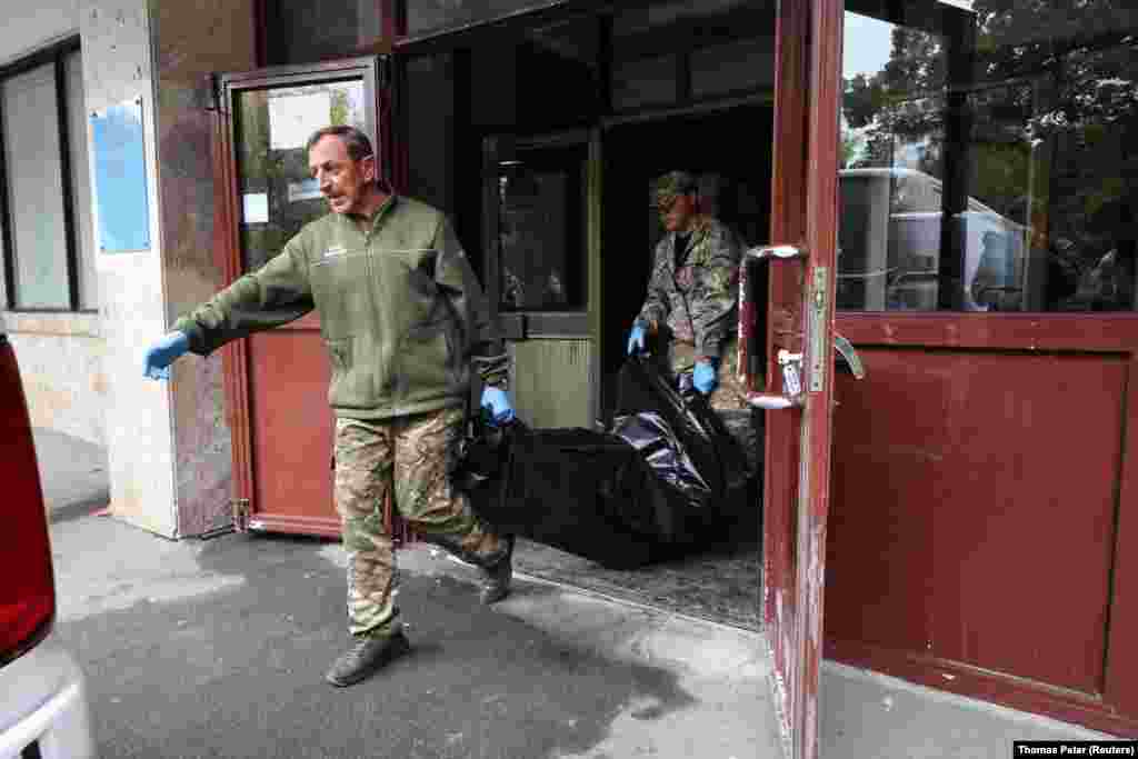 Поліцейські виносять тіло загиблого внаслідок російського удару по Інституту кардіології у Києві