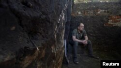 Український військовослужбовець 113-ї бригади територіальної оборони ЗСУ, сидить на ящику від боєприпасів у недобудованому бліндажі біля лінії фронту в Харківській області, Україна, 28 травня 2024 року