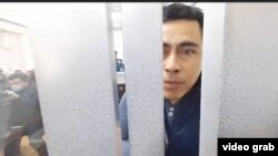 Өзбек блогері Отабек Саттори сот залындағы қоршаудан қарап тұр. Сұрхандария облысы Музрабад ауданы, 11 наурыз, 2021 жыл. Видоедан скриншот.
