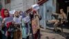 A Taliban fighter watches as Afghan women hold placards during a demonstration demanding better rights for women in front of the former Women's Affairs Ministry in Kabul on September 19.