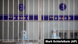 Офіцери служби безпеки в захисних костюмах стоять біля приймальні в залі для відвідувачів у центрі ув’язнення Урумчі № 3 у Дабанченгу в Сіньцзян-Уйгурському автономному районі на заході Китаю, 23 квітня 2021 року. Урумчі № 3, найбільший центр ув’язнення Китаю. Площею він удвічі більший за Ватикан, і вміщає щонайменше 10 000 в’язнів.